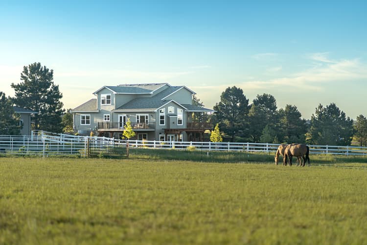 an exterior photo of a home on a horse ranch with horses in the foreground